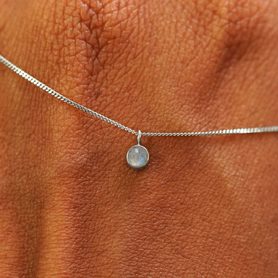 Close up view of a 14k white gold Labradorite Necklace draped across the back of a model's hand