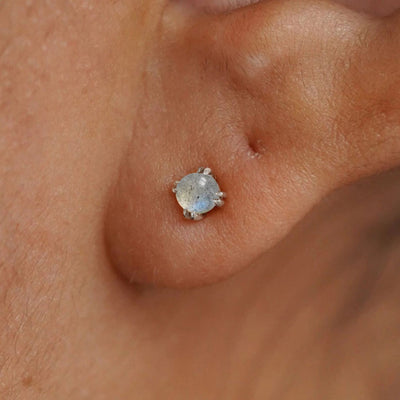 Close up view of a model's ear wearing a white gold labradorite earring