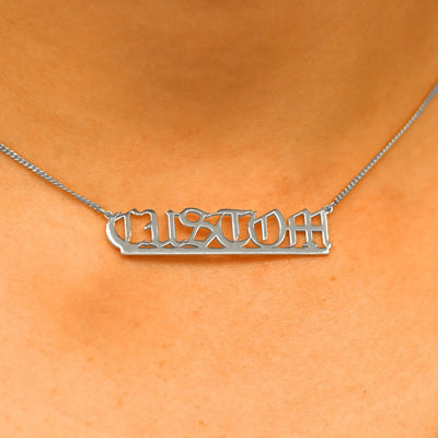 Close up view of a model's neck wearing a Large Custom Nameplate necklace that reads the word Custom