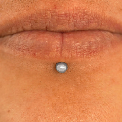Close up view of a model's lips wearing a 14k white gold Large Labret Piercing