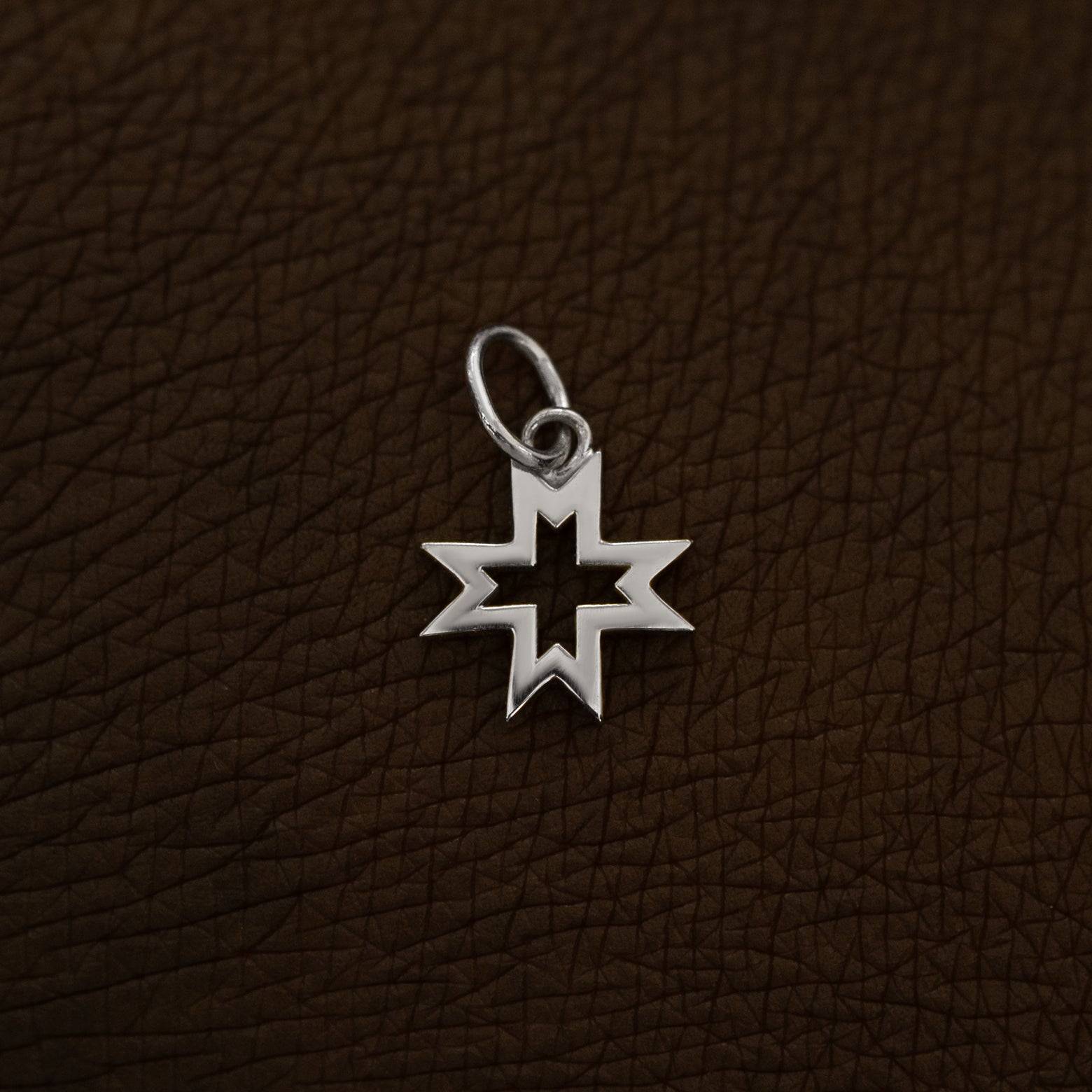 A 14 karat white solid gold Large Open 8 Pointed Star Charm on the back of a model's hand