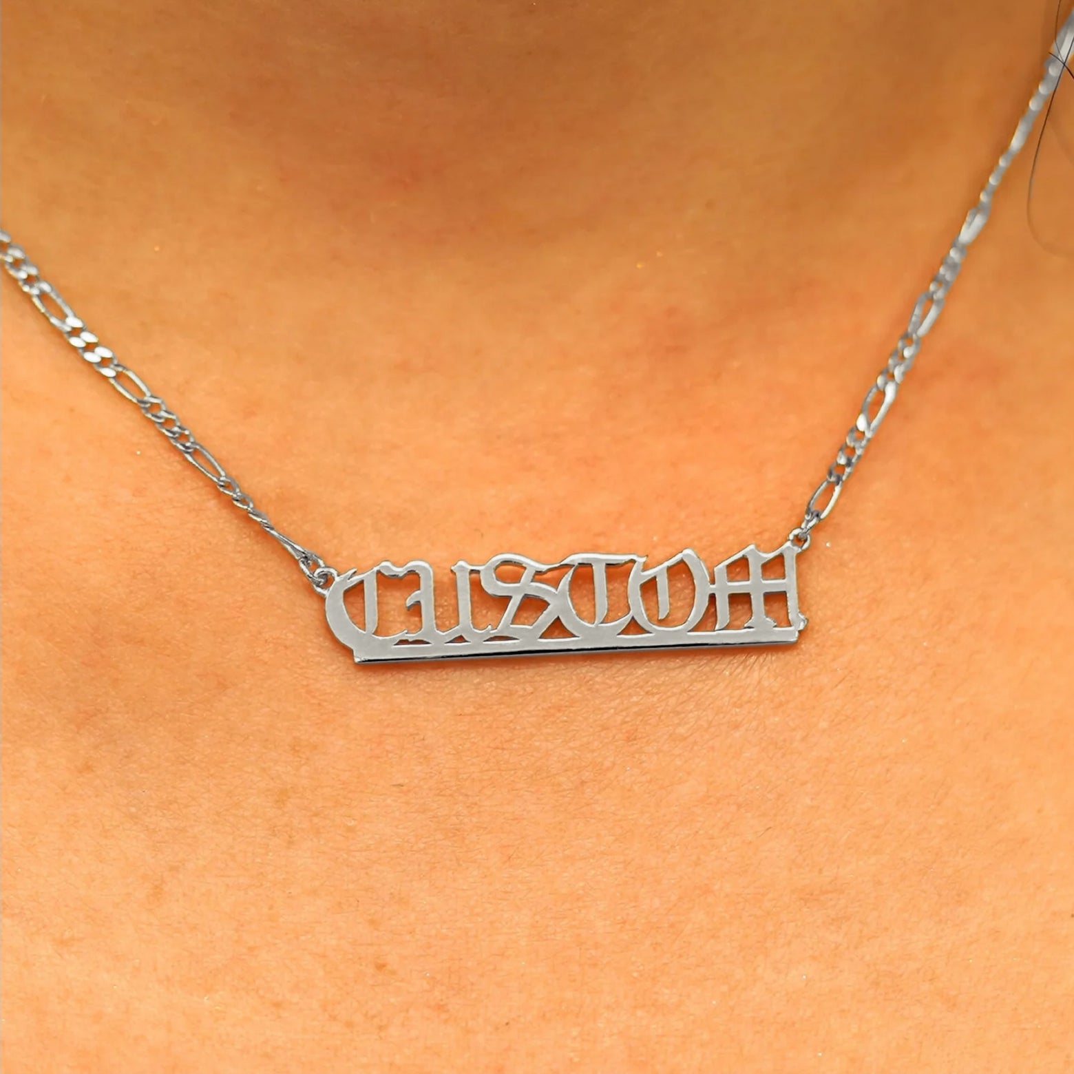Close up view of a model's neck wearing a Medium Custom Nameplate necklace that reads the word Custom