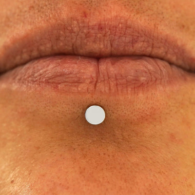 Close up view of a model's lips wearing a 14k white gold Medium Circle Flatback in a labret piercing
