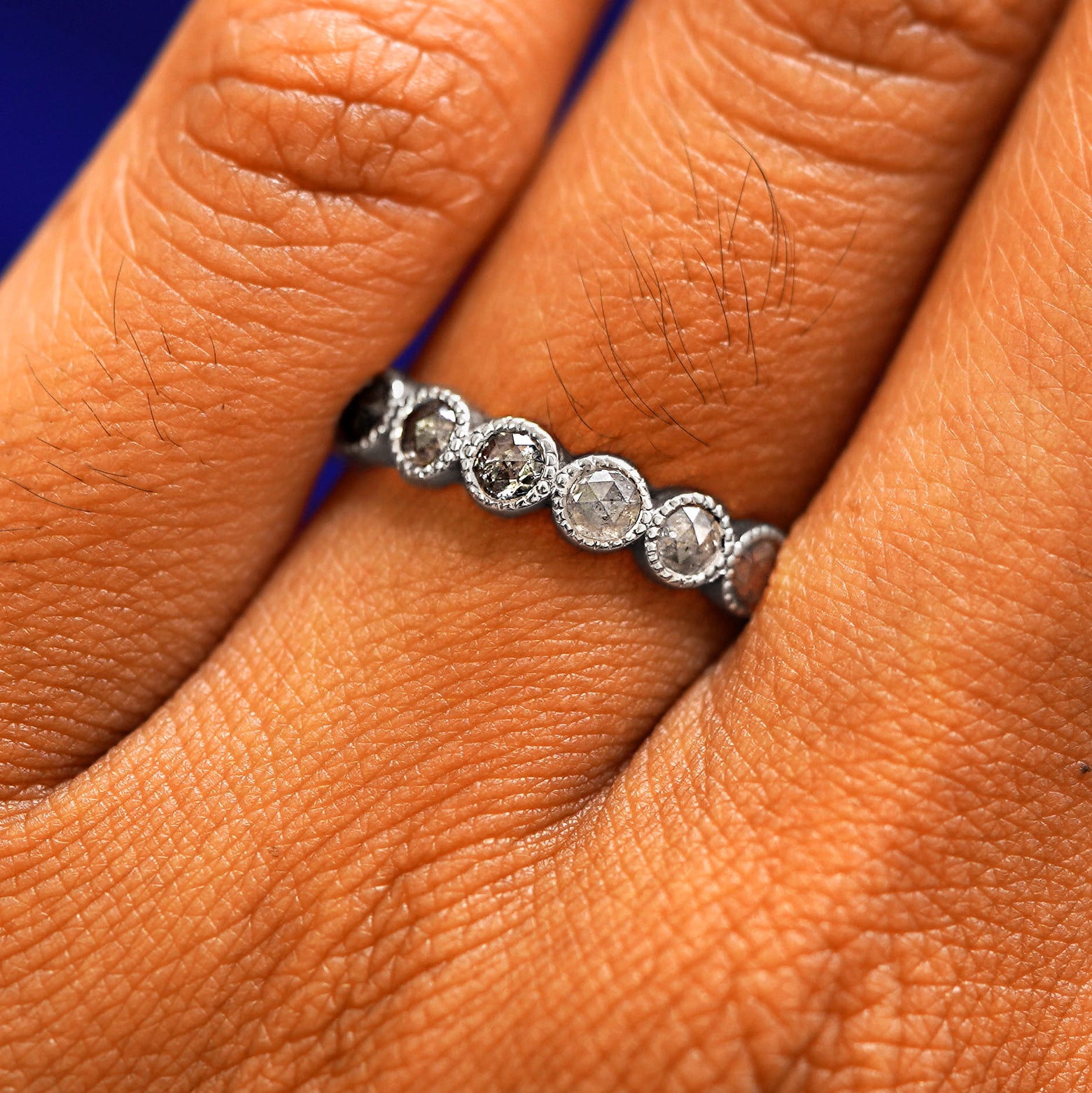 Close up view of a model's hand wearing a 14k white gold Milgrain Diamond Band