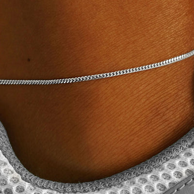 Close up view of a model's ankle wearing a solid white gold Mini Miami Anklet