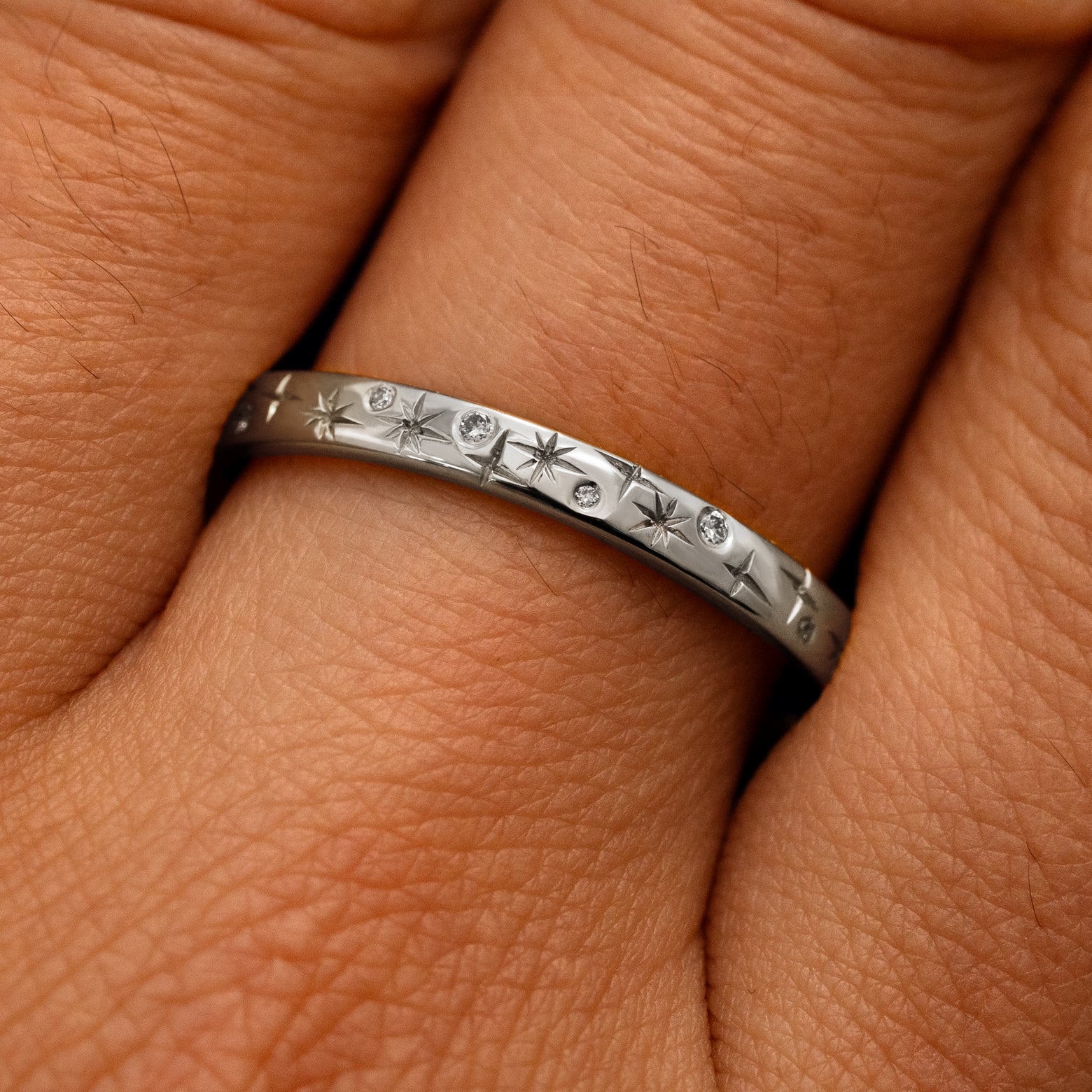 Close up view of a model's fingers wearing a 14k white gold Mixed Diamond Stars Band