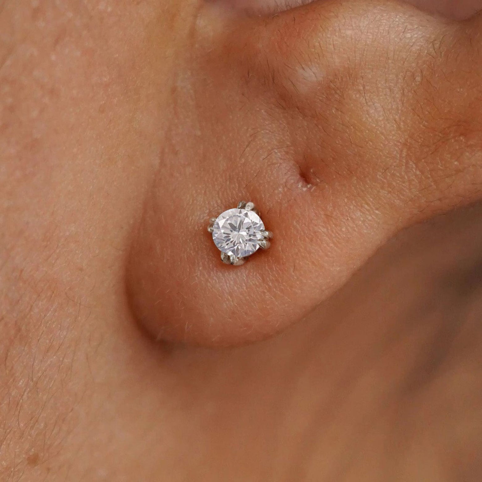 Close up view of a model's ear wearing a 14k white gold Moissanite Stud Earring
