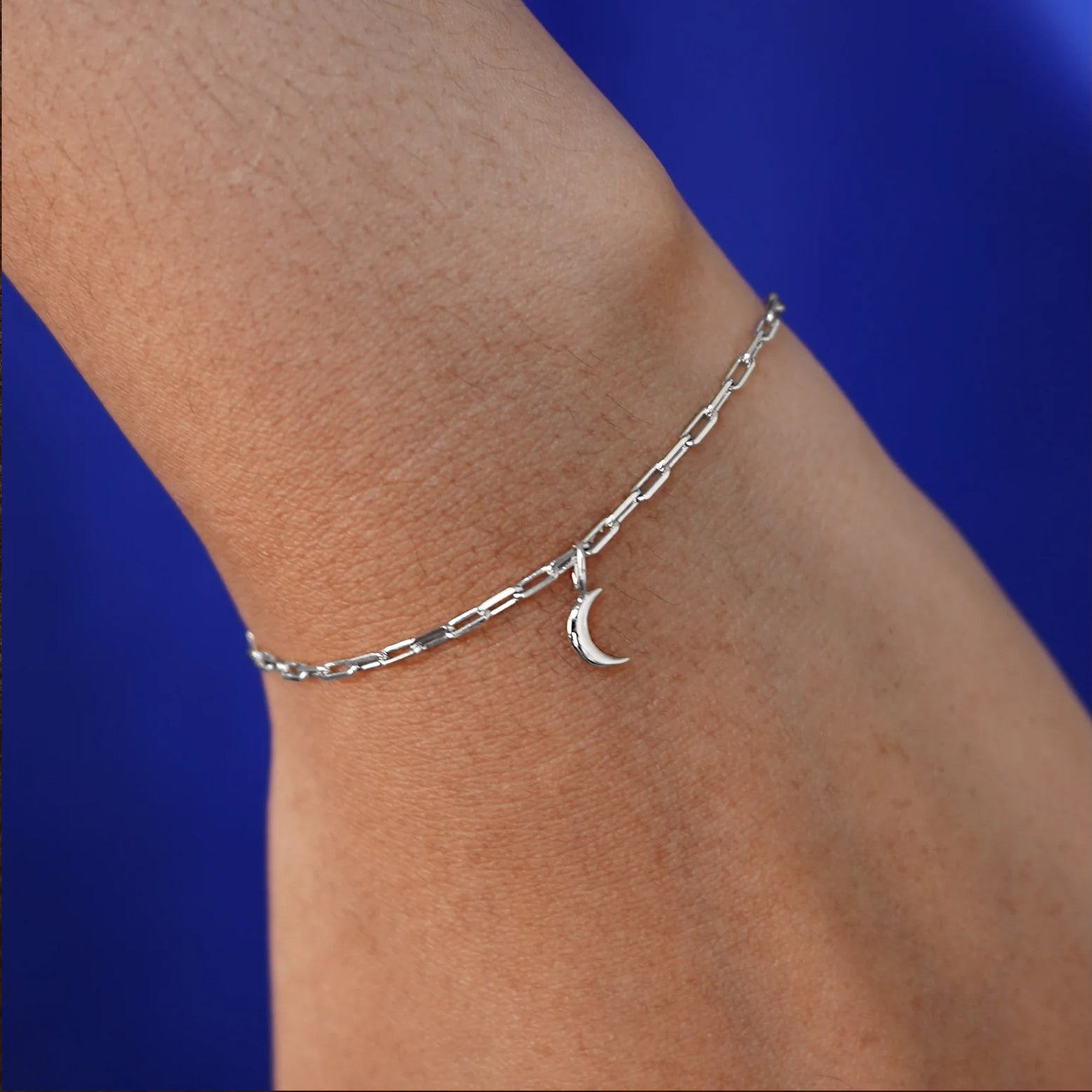 Close up view of a model's wrist wearing a white gold Moon Charm on a Butch Chain Bracelet