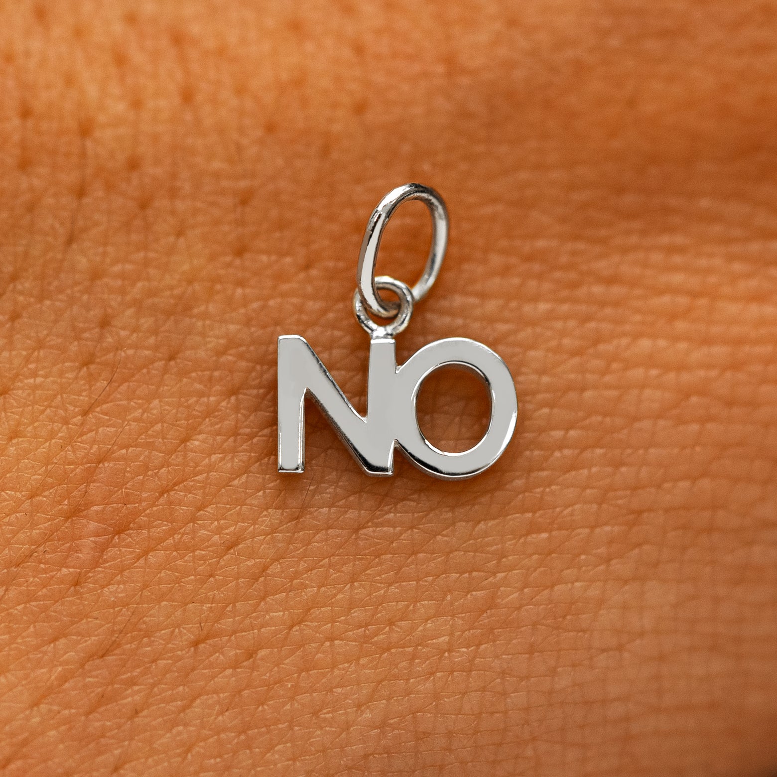A solid 14k white gold No Charm on the back of a models hand
