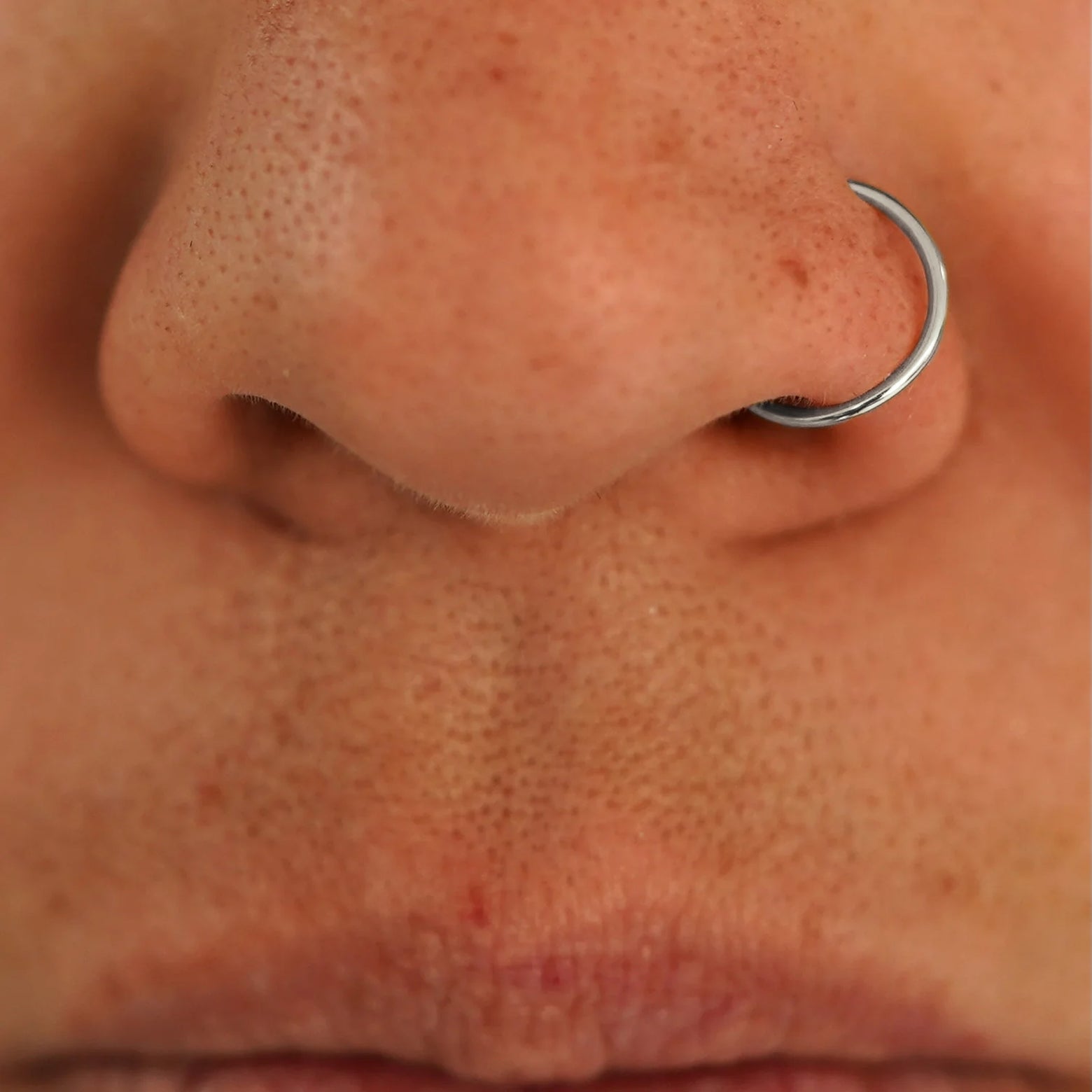 Close up view of a model's nose wearing a 14k white gold Nose Ring Hoop