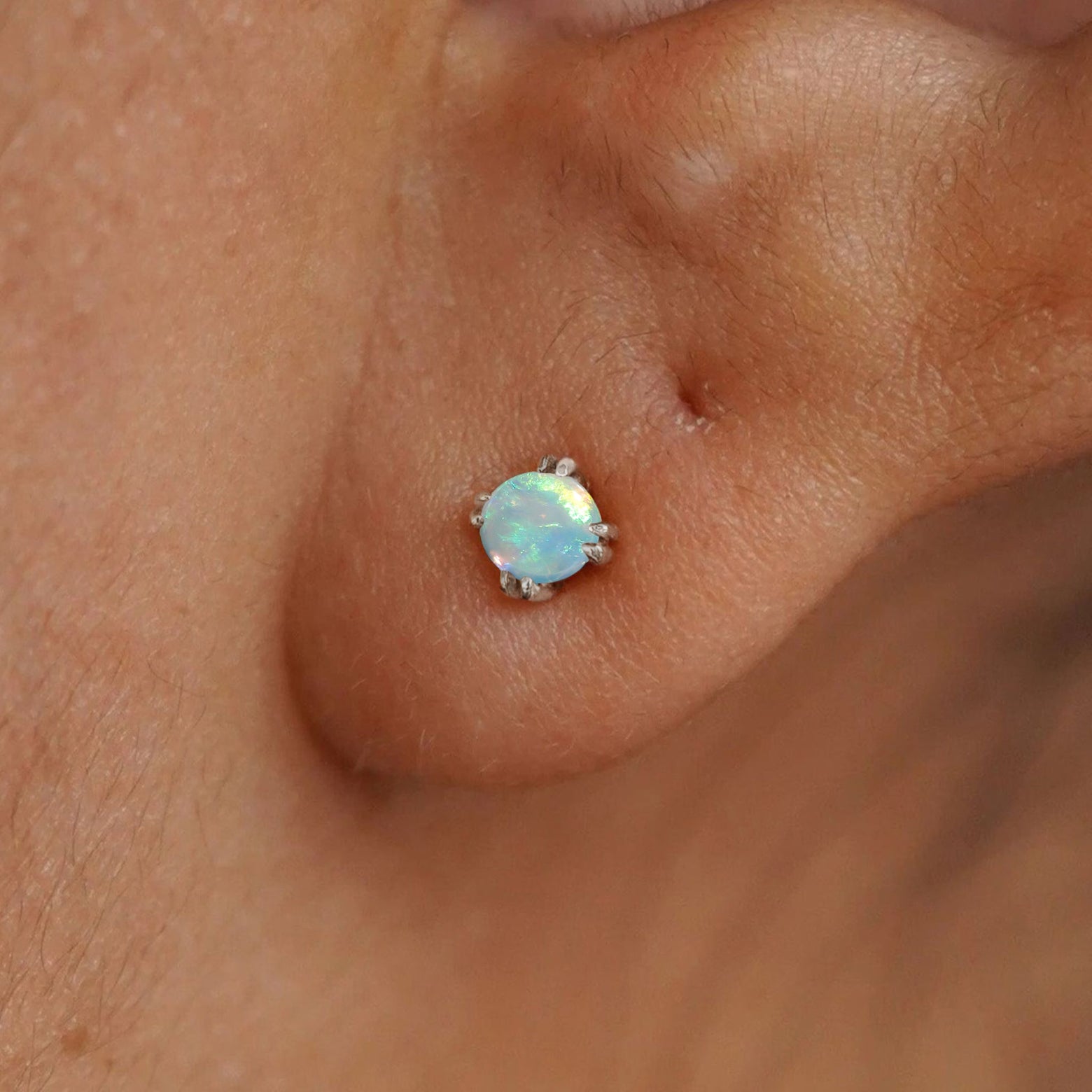 Close up view of a model's ear wearing a 14k white gold Opal Earring