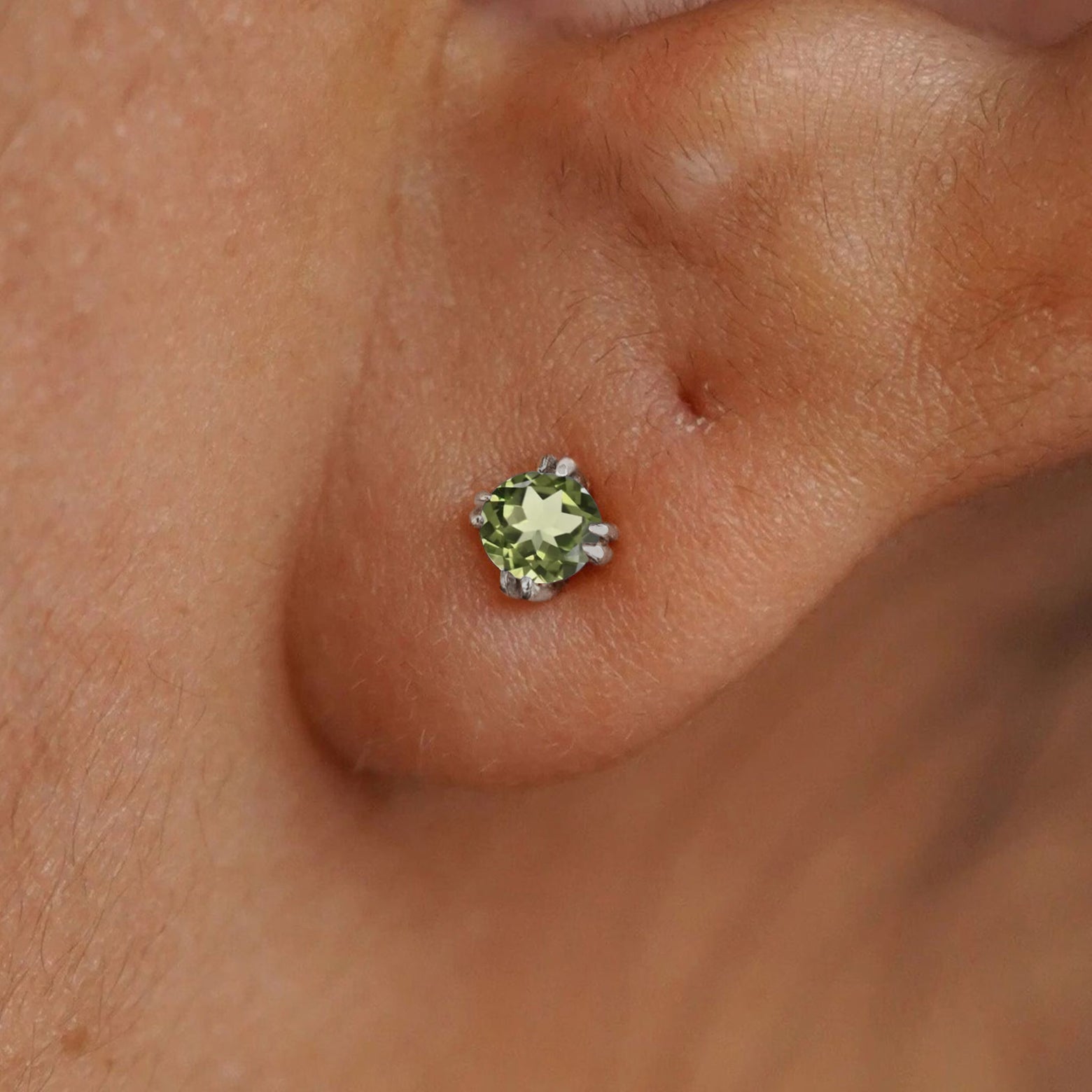 Close up view of a model's ear wearing a 14k white gold Peridot Earring