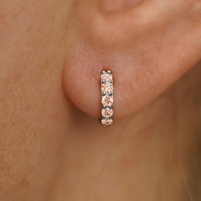 Close up view of a model's ear wearing a white gold Mini Pink Lab Diamond Huggie Hoop