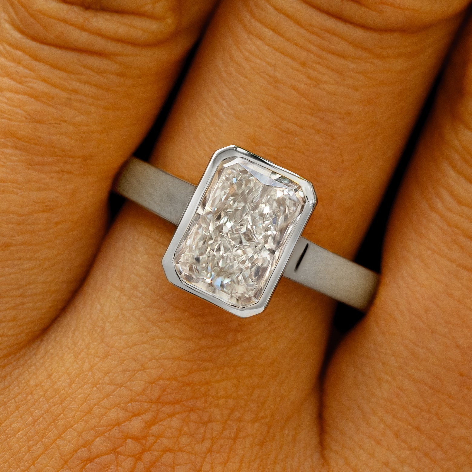A solid 14k white gold Radiant Cut Lab Diamond Cathedral Ring on a model's finger