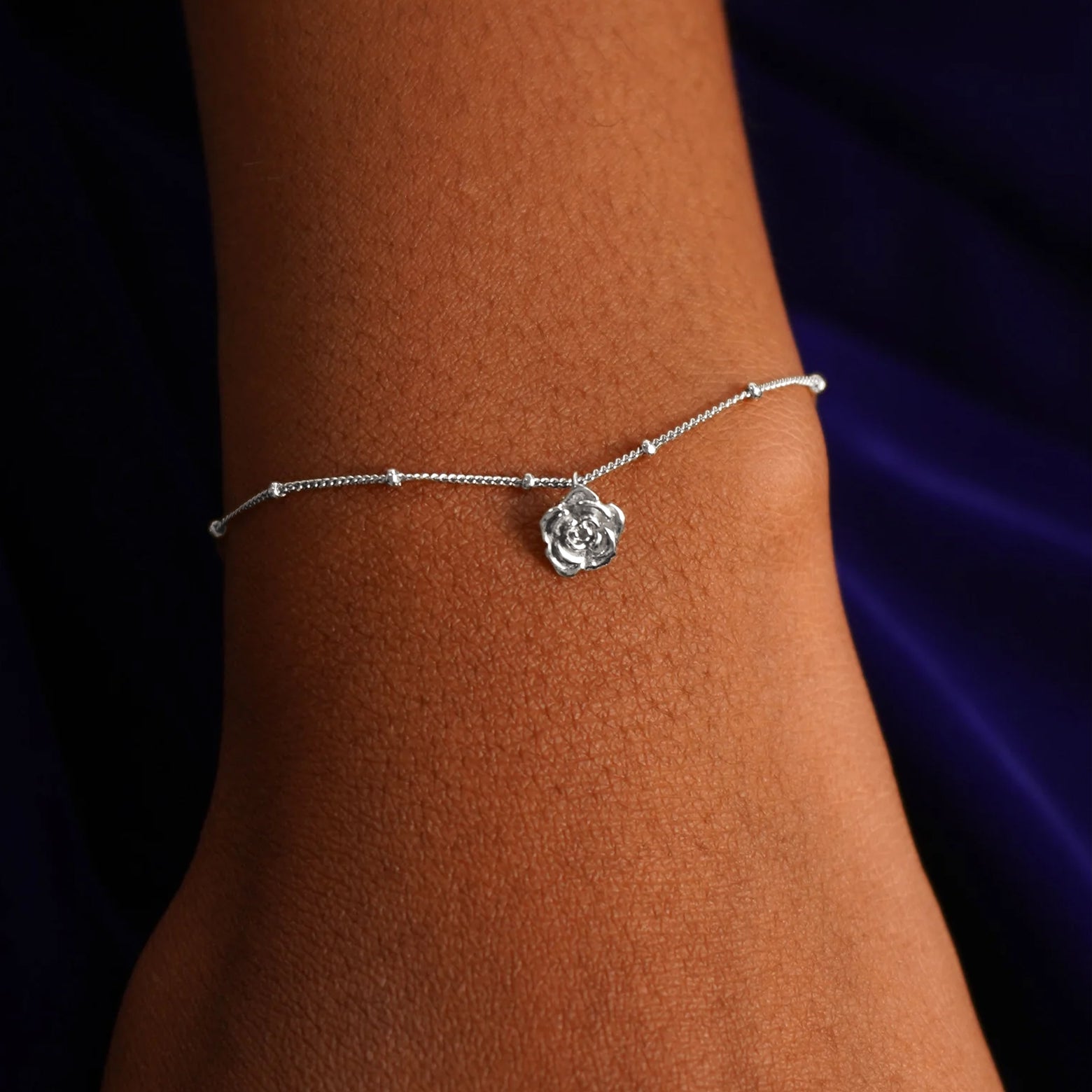 Close up view of a model's wrist wearing a white gold Rose Charm on a Beaded Essential Chain