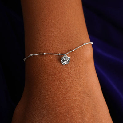 Close up view of a model's wrist wearing a white gold Rose Charm on a Beaded Essential Chain