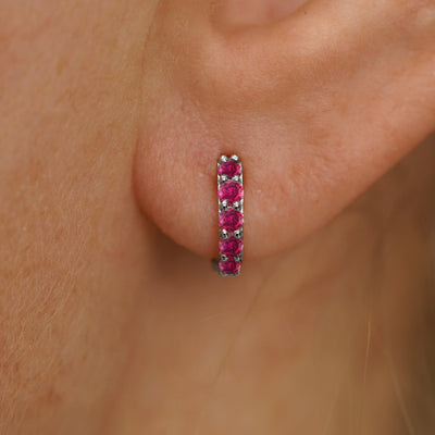 Close up view of a model's ear wearing a white gold Mini Ruby Huggie Hoop