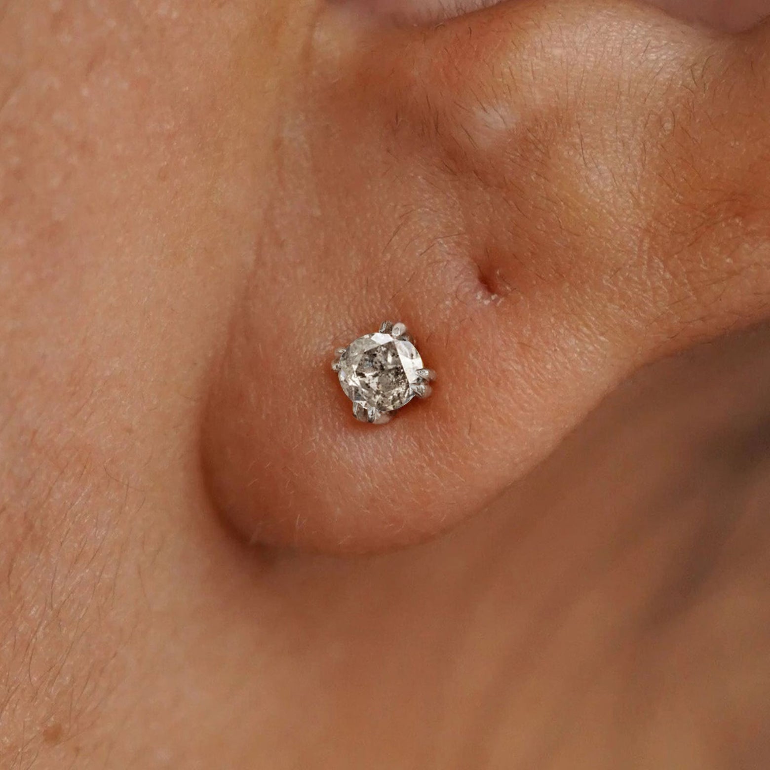A model's ear wearing a 14k white gold Salt and Pepper Diamond Earring