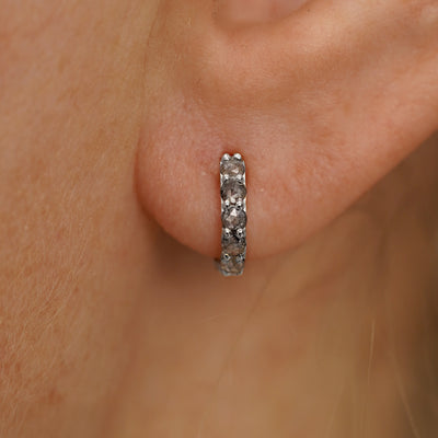 Close up view of a model's ear wearing a white gold Mini Salt and Pepper Diamond Huggie Hoop