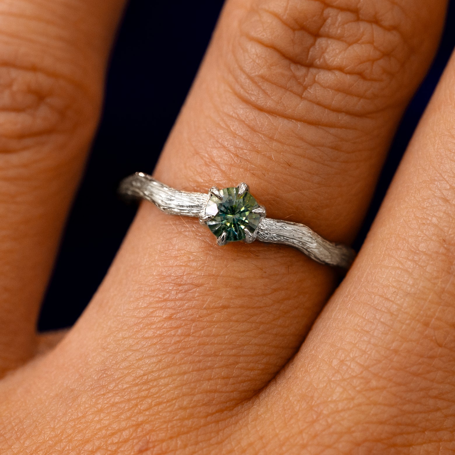 A solid 14k white gold Montana Teal Sapphire Waved Branch Ring on a model's finger