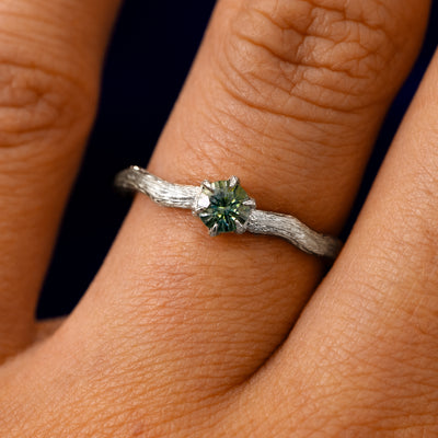 A solid 14k white gold Montana Teal Sapphire Waved Branch Ring on a model's finger
