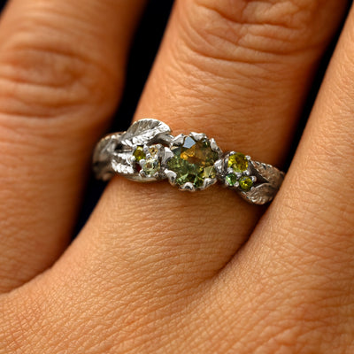 Close up view of a model's fingers wearing a 14k white gold Green Sapphire Leaves and Vines Ring