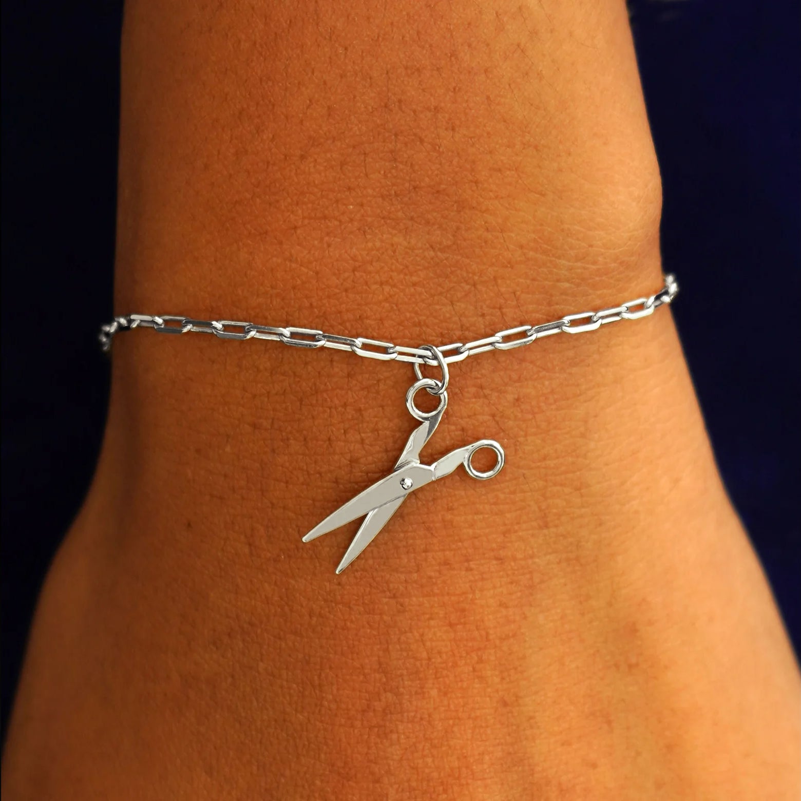 Close up view of a model's wrist wearing a white gold Scissors Charm on a Butch Chain Bracelet