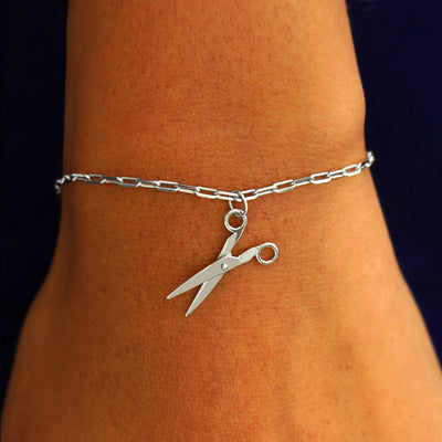 Close up view of a model's wrist wearing a white gold Scissors Charm on a Butch Chain Bracelet