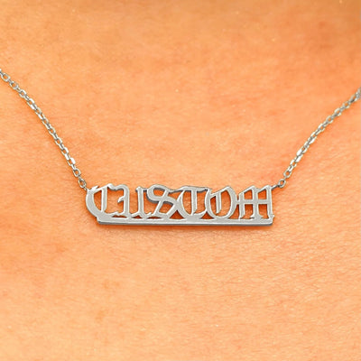 Close up view of a model's neck wearing a Small Custom Nameplate necklace that reads the word Custom