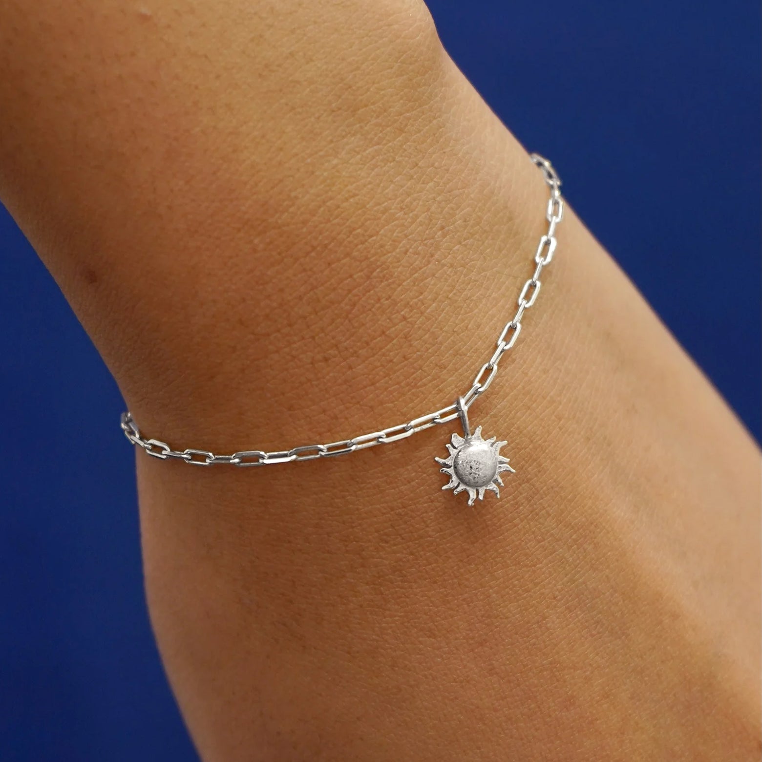 Close up view of a model's wrist wearing a white gold Sun Charm on a Butch Chain Bracelet