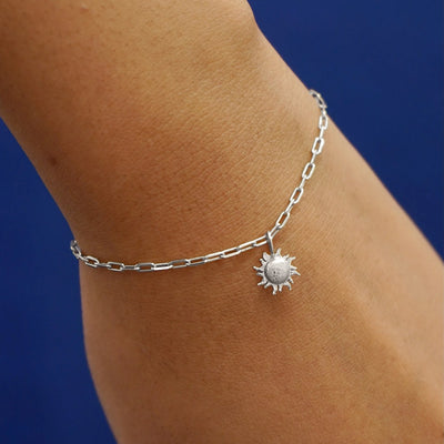 Close up view of a model's wrist wearing a white gold Sun Charm on a Butch Chain Bracelet