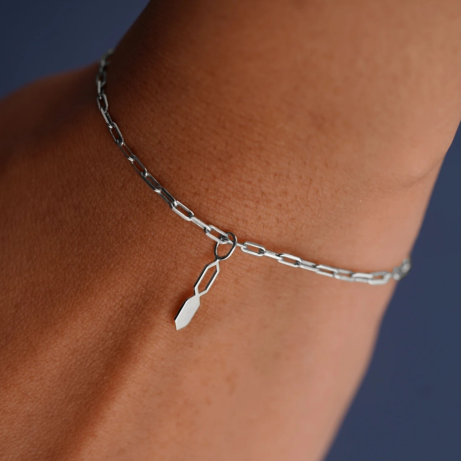 Close up view of a model's wrist wearing a white gold Tanlah Charm on a Butch Bracelet