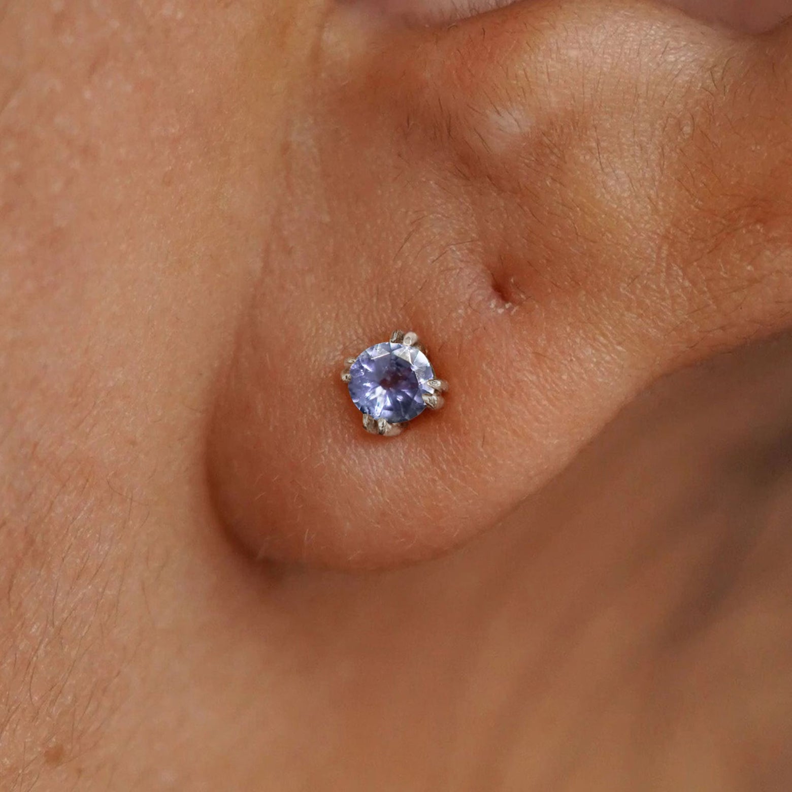 Close up view of a model's ear wearing a 14k white gold Tanzanite Earring