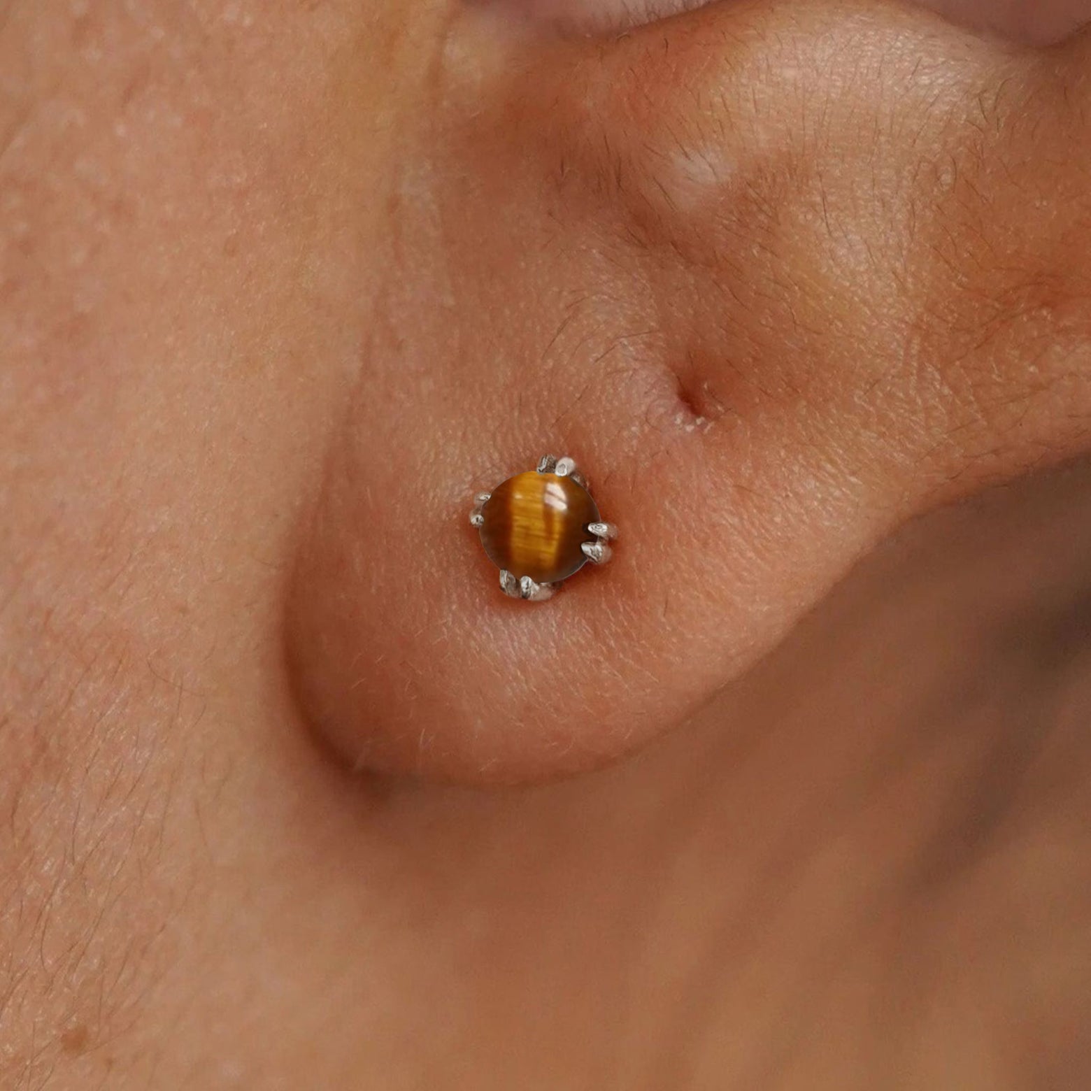 Close up view of a model's ear wearing a 14k white gold Tiger Eye Earring