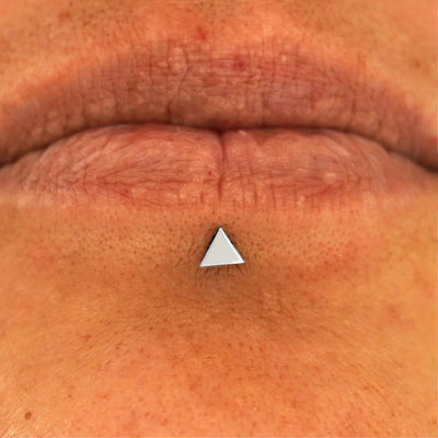 Close up view of a model's lips wearing a 14k white gold Triangle Flatback in a labret piercing