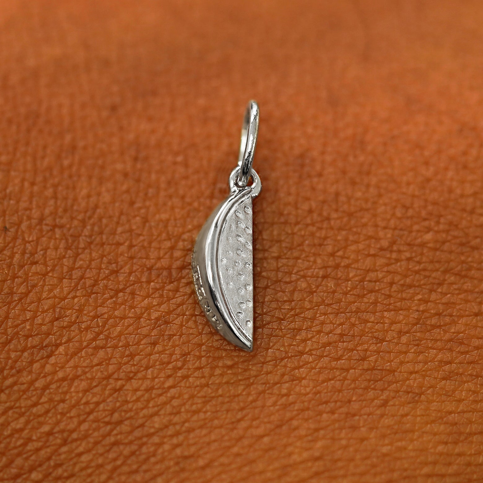 A solid 14k white gold Watermelon Charm resting on the back of a model's hand