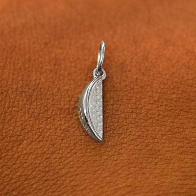 A solid 14k white gold Watermelon Charm resting on the back of a model's hand