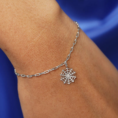 Close up view of a model's wrist wearing a white gold Spider Web Charm on a Butch Chain Bracelet