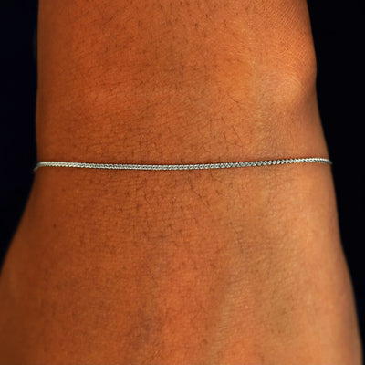 A model's wrist wearing a solid 14k white gold Wheat Chain