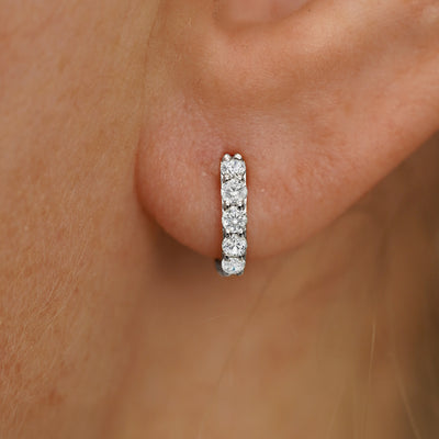 Close up view of a model's ear wearing a white gold Mini Lab White Diamond Huggie Hoop