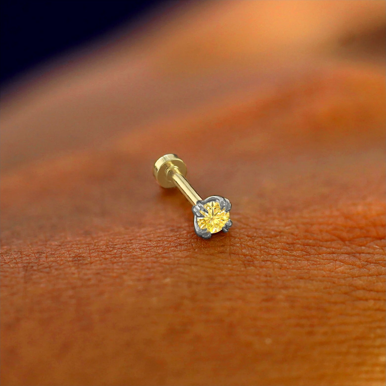 A solid 14k white gold Yellow Diamond Piercing resting on the back of a model's hand