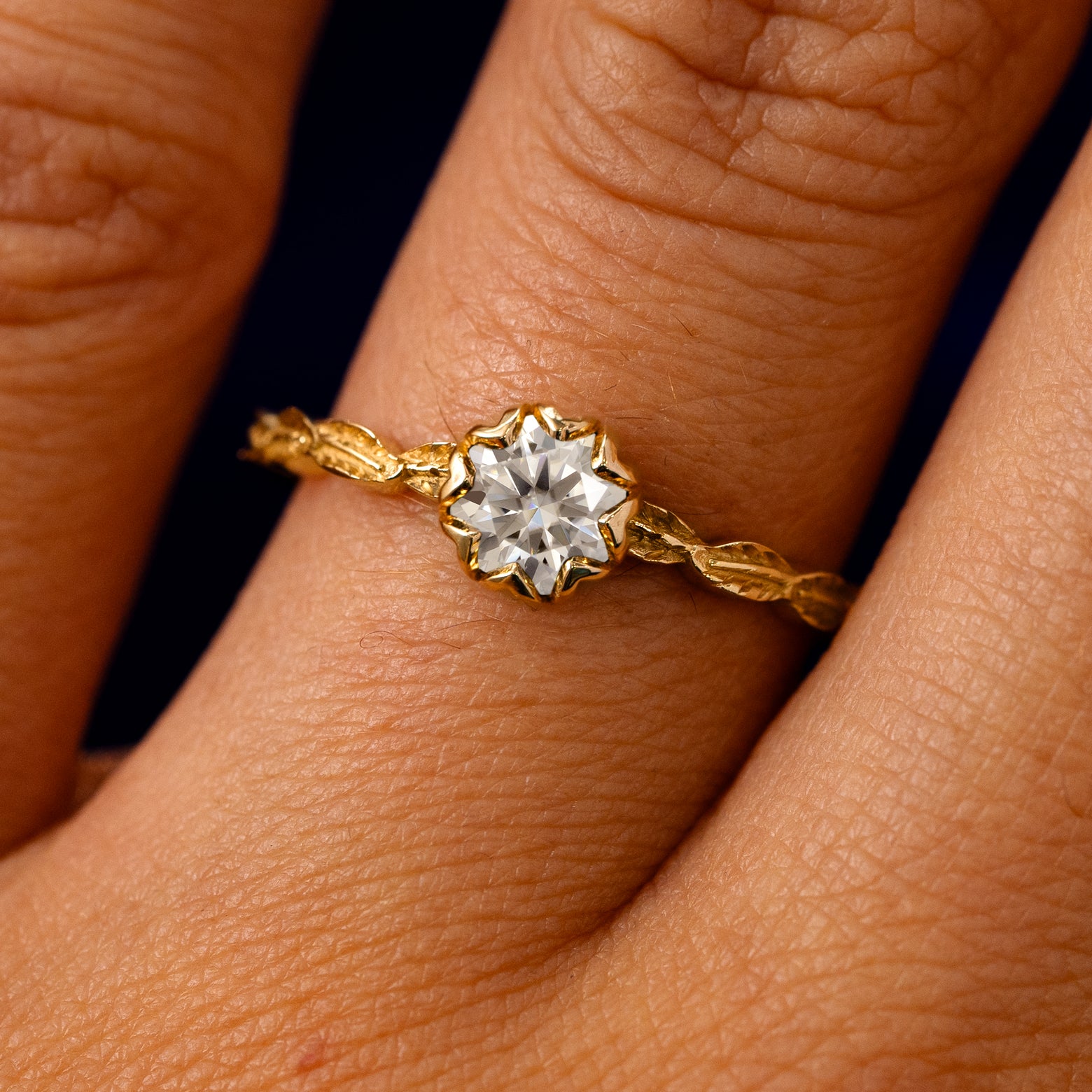 A solid 14k yellow gold White Moissanite Leaf Ring on a model's finger