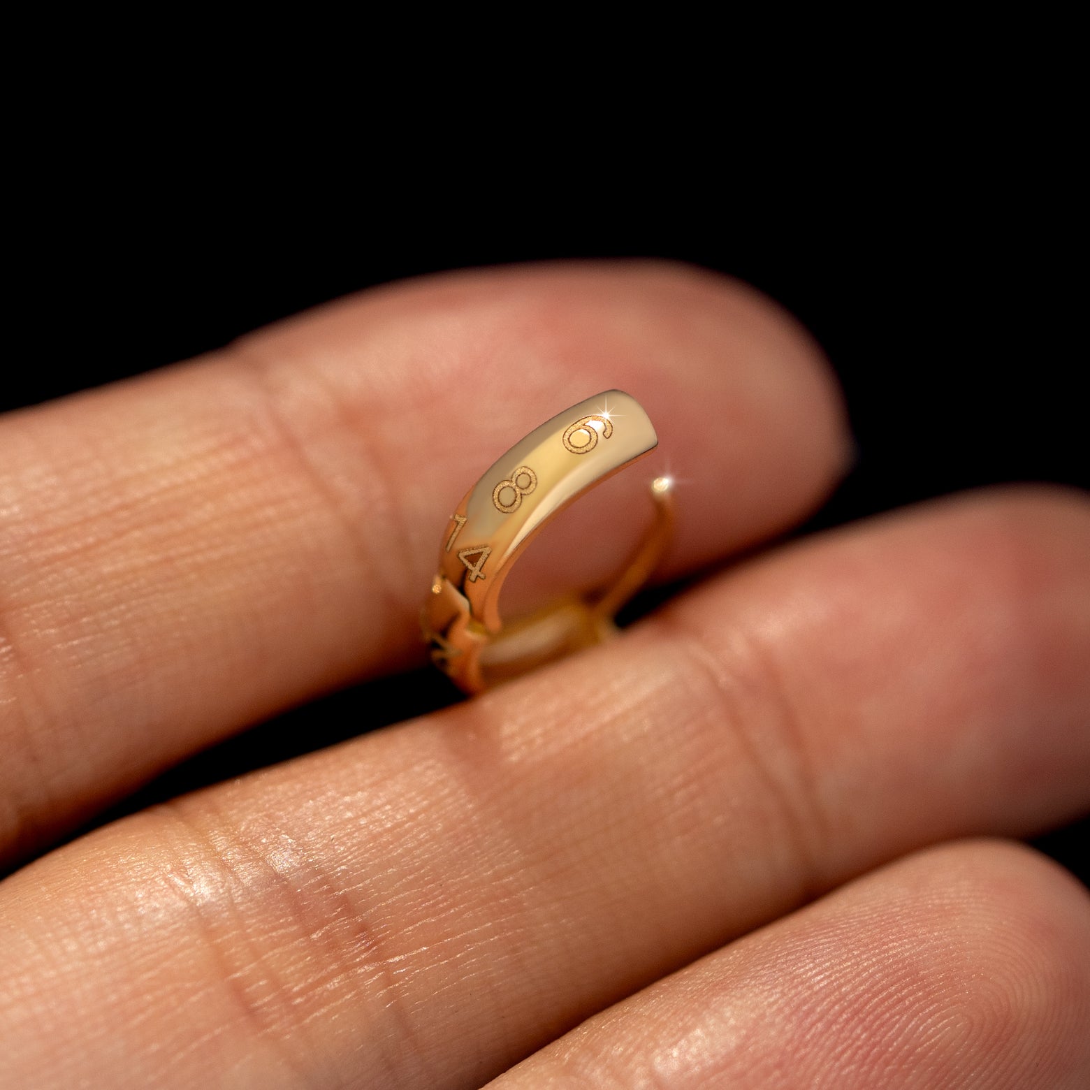 A wide huggie hoop with numbers engraved on the back