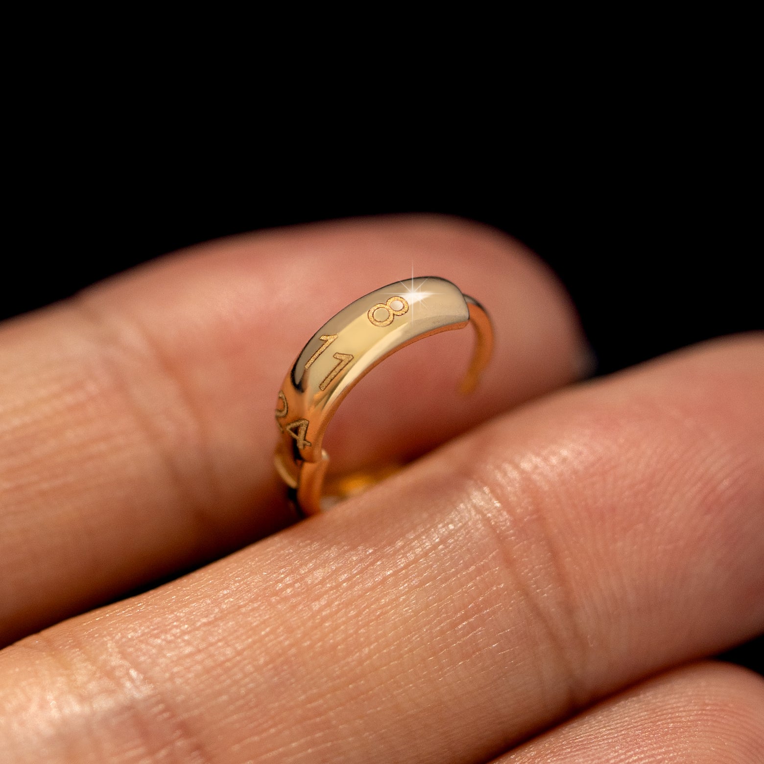 A wide huggie hoop with numbers engraved on the front