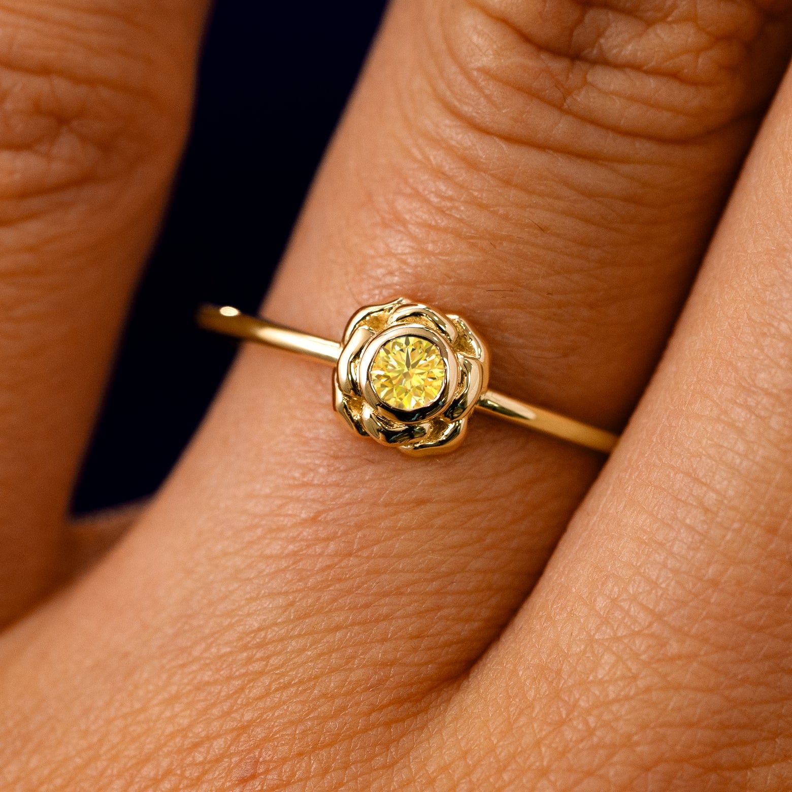 A solid 14k yellow gold Yellow Diamond Flower Ring on a model's finger