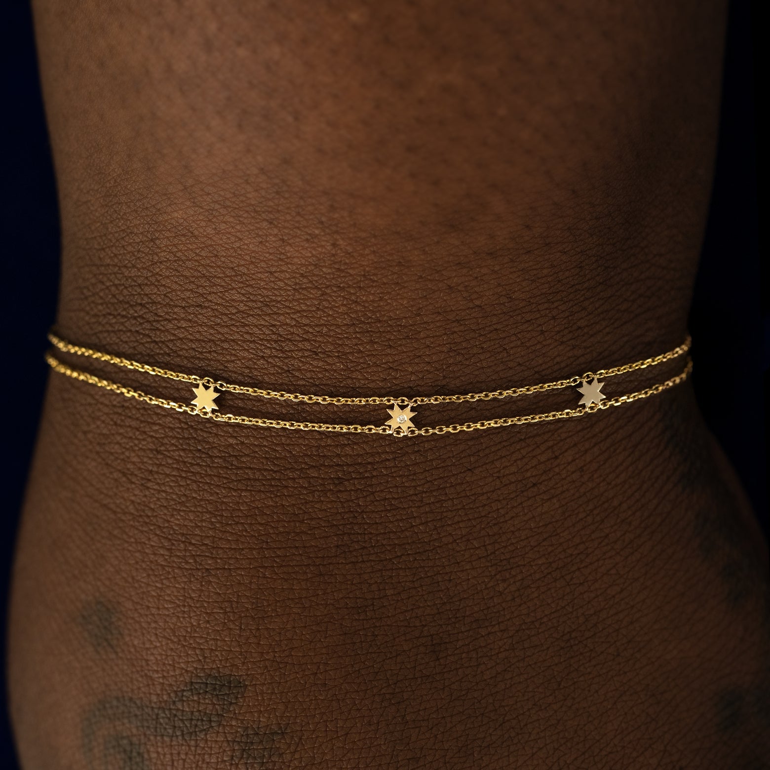 A model wearing a yellow gold 8 pointed star bracelet