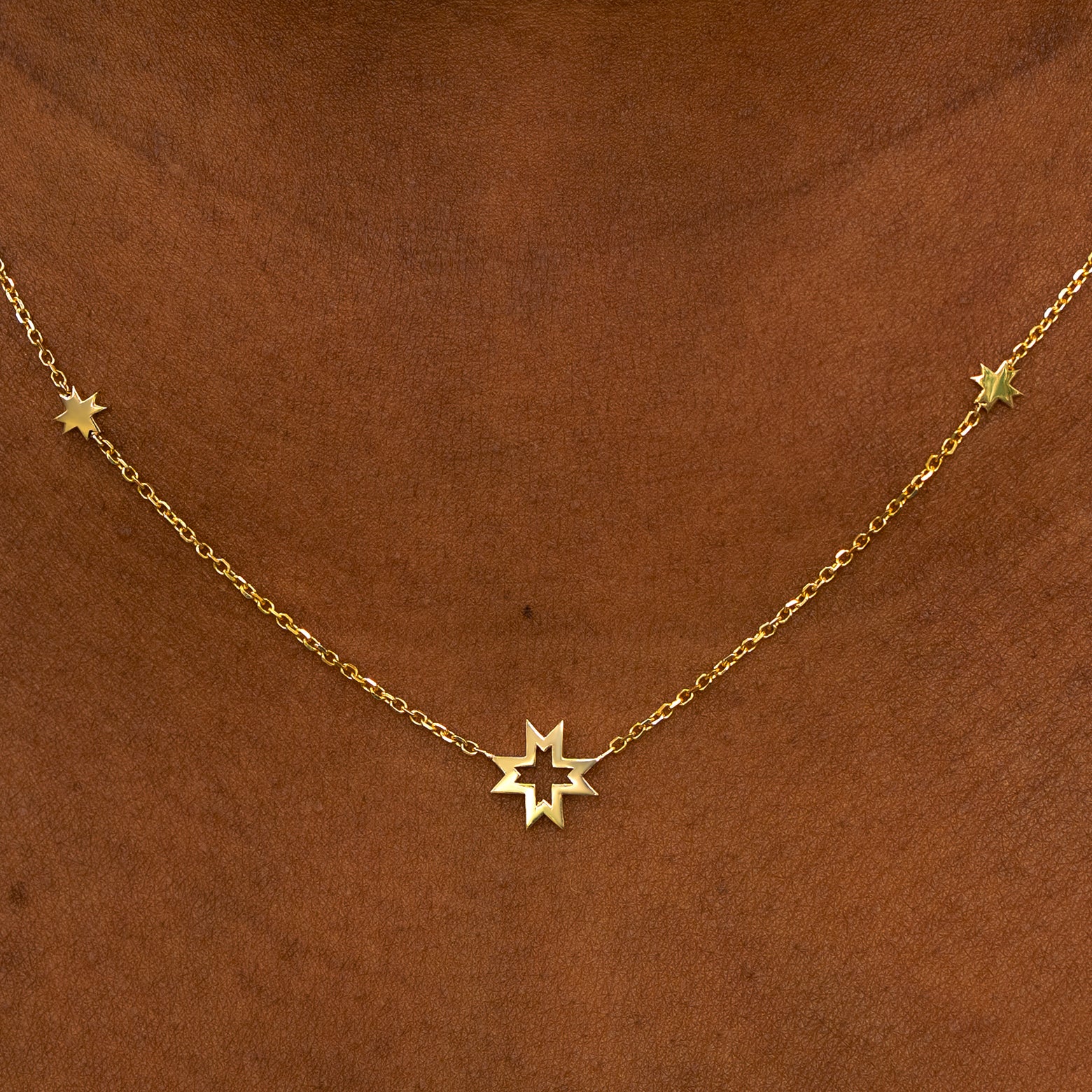 A model wearing a yellow gold 8 pointed stars station necklace