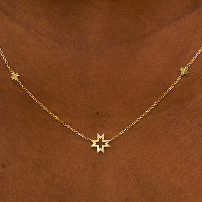 A model wearing a yellow gold 8 pointed stars station necklace