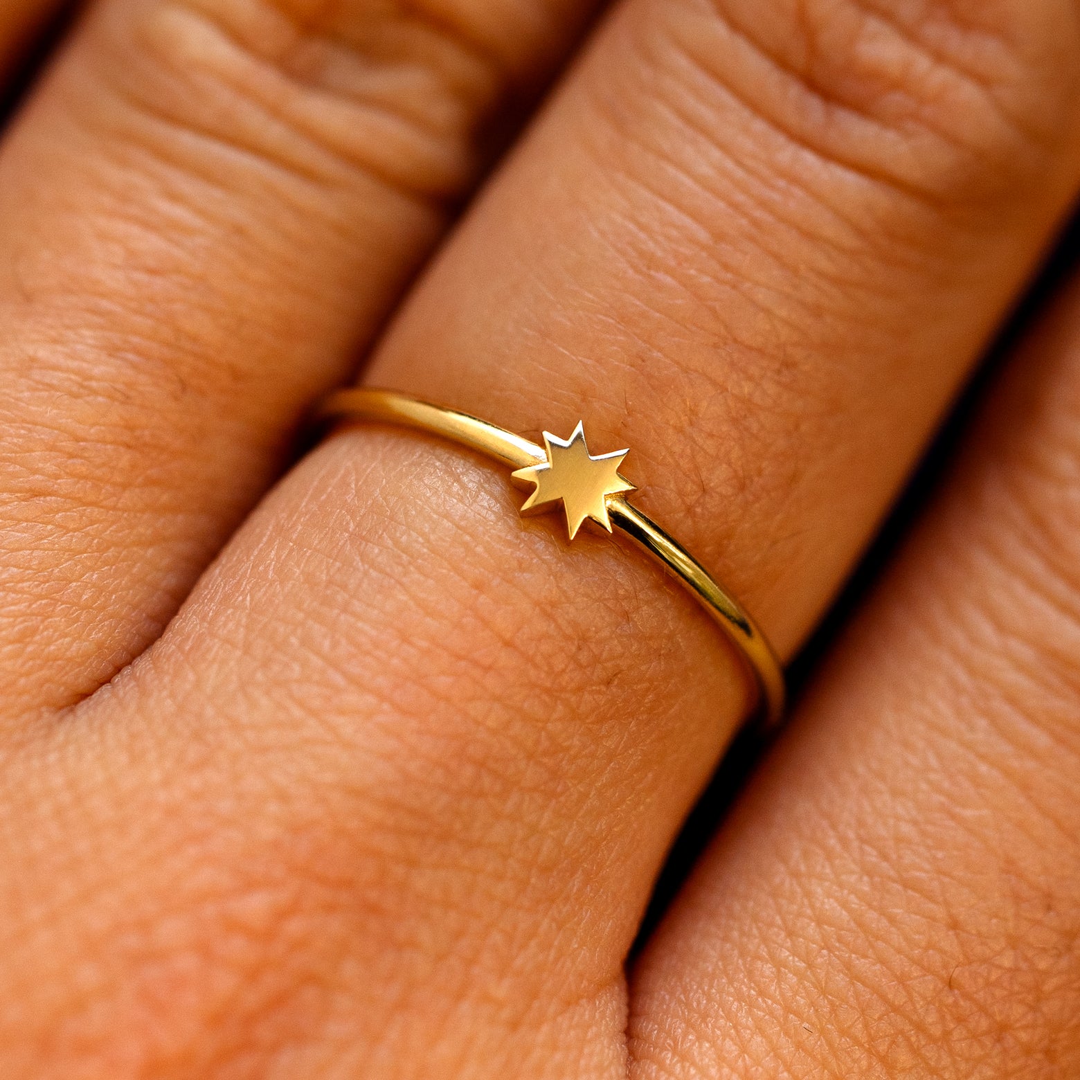 Close up view of a models fingers wearing a yellow gold 8 pointed star ring