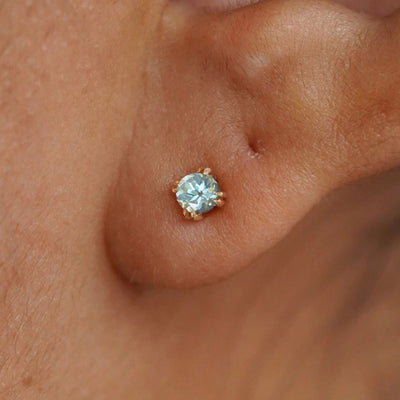 Close up view of a model's ear wearing a 14k yellow gold Aquamarine Earring